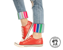Load image into Gallery viewer, Red sneakers with colorful rolled-up jeans and rainbow striped good guys Chucky cosplay pants cuffs on a white background, featuring the Boots &amp; Brothers logo.